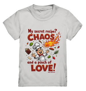 Ein cartoonhafter Koch mit weißem Kochhut und weiß-rotem Kochkittel, der fröhlich und mit ausgestreckten Armen lacht. Er steht inmitten eines Wirbels von Zutaten, darunter Flammen, Gemüse, Tomaten, und ein Kochbuch, die in der Luft herumfliegen. Der Koch Bright Lights Arts