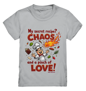 Ein cartoonhafter Koch mit weißem Kochhut und weiß-rotem Kochkittel, der fröhlich und mit ausgestreckten Armen lacht. Er steht inmitten eines Wirbels von Zutaten, darunter Flammen, Gemüse, Tomaten, und ein Kochbuch, die in der Luft herumfliegen. Der Koch Bright Lights Arts