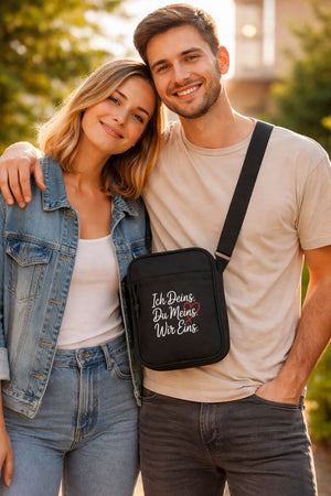 Schwarze Umhängetasche mit weiß-rotem Liebes-Schriftzug „Ich Deins. Du Meins. Wir Eins.“ getragen von einem verliebten Paar im Alltag – minimalistisches Geschenk für Paare