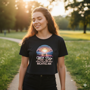 Lächelnde Frau im schwarzen Cropped Tee mit Sonnenuntergang-Print in einem sonnigen Park, High-Key Licht, emotionaler Vibe.