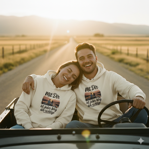 Paar im Cabrio bei Sonnenuntergang trägt Partner-Hoodies mit 'Mit Dir ist jeder Weg der richtige' Print, warme Roadtrip-Vibe