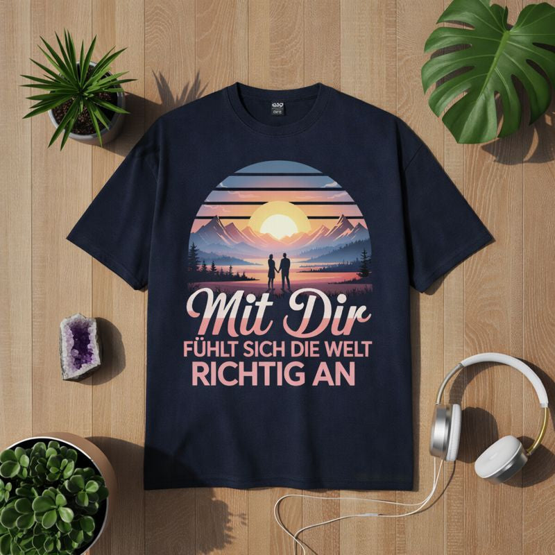 Blaues T-Shirt mit romantischem Paar-Motiv vor Berglandschaft bei Sonnenuntergang und Schriftzug „Mit Dir fühlt sich die Welt richtig an“, emotionales Liebes- und Verbundenheitsdesign – Bright Light Arts