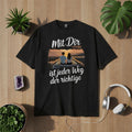 Schwarzes T-Shirt mit romantischem Paar-Motiv beim Roadtrip und Spruch „Mit Dir ist jeder Weg der richtige“, emotionales Liebesdesign für Paare, Reisen & Verbundenheit – Bright Light Arts