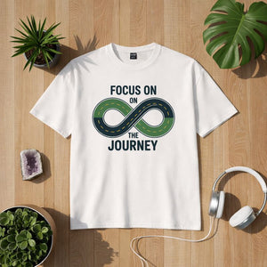Bright Light Arts Premium T-Shirt „Focus on the Journey“ mit Unendlichkeits-Straßenmotiv als Lifestyle-Mockup auf hellem Hintergrund
