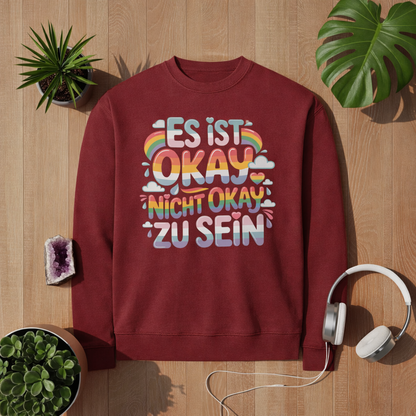 Rotes Premium Sweatshirt mit „Es ist okay nicht okay zu sein“ Design in bunten Regenbogenfarben – positives Mental Health Statement von Bright Lights Arts