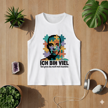 Weißes Herren Tanktop mit „Ich bin viel“ Autismus Puzzle Portrait Design als Flatlay auf hellem Holzboden mit Pflanzen und Kopfhörern – modernes Lifestyle Mockup