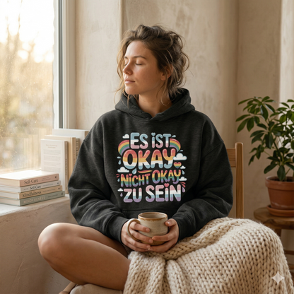 Person im oversized Bright Lights Arts Bio-Hoodie mit dem Pastell-Schriftzug Es ist okay nicht okay zu sein.