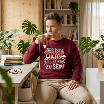 erson im schwarzen 280 GSM Bio-Sweatshirt mit dem Bubbly-Schriftzug Es ist okay nicht okay zu sein.
