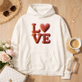 Oversized Hoodie aus Bio-Baumwolle in Off-White mit 3D-Ballon-Schriftzug „LOVE“ und Herzmotiv, liebevolles Statement-Design im warmen Lifestyle-Setting – Bright Light Arts