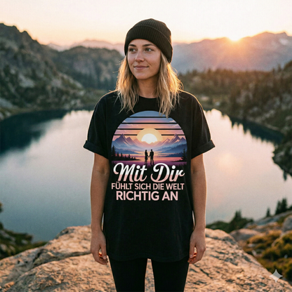 Frontansicht einer Frau im Oversized-T-Shirt mit dem Aufdruck „Mit Dir FÜHLT SICH DIE WELT RICHTIG AN“ an einem Bergsee